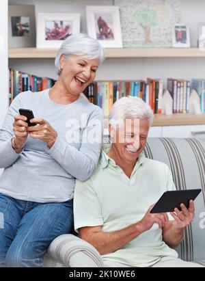 Who needs the phonebook. A senior woman texting while her husband wotks on a digital tablet. Stock Photo