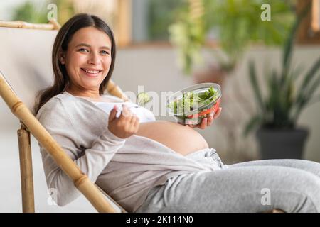 Beautiful Young Pregnant Woman Eating Fresh Vegetable Salad At Home Stock Photo