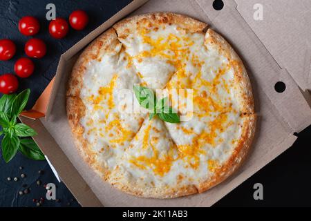 Pizza in a cardboard box on a black chalkboard background. View from above Stock Photo