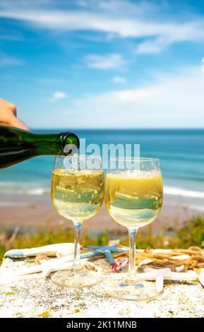 Tasting of txakoli or chacolí slightly sparkling very dry white wine produced in Spanish Basque Country, served outdoor with view on Bay of Biscay, At Stock Photo