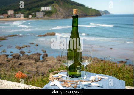 Tasting of txakoli or chacolí slightly sparkling very dry white wine produced in Spanish Basque Country, served outdoor with view on Bay of Biscay, At Stock Photo