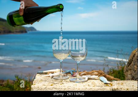 Pouring of txakoli or chacolí slightly sparkling very dry white wine produced in Spanish Basque Country, served outdoor with view on Bay of Biscay, At Stock Photo