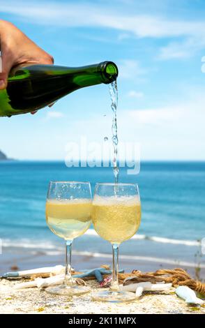 Pouring of txakoli or chacolí slightly sparkling very dry white wine produced in Spanish Basque Country, served outdoor with view on Bay of Biscay, At Stock Photo