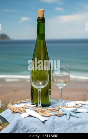 Tasting of txakoli or chacolí slightly sparkling very dry white wine produced in Spanish Basque Country, served outdoor with view on Bay of Biscay, At Stock Photo