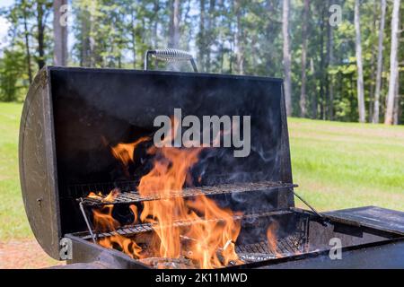 In preparation for grilling with firewood, prepare a BBQ with a blazing fire to cook the meat Stock Photo