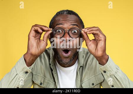 Surprised happy funny excited mature black male in casual and glasses with open mouth look at camera Stock Photo