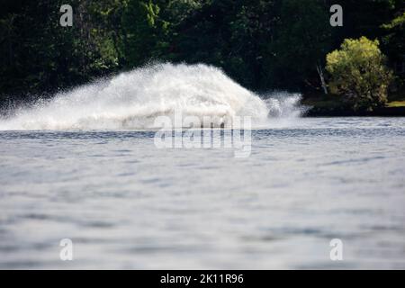 Wave and splash of water is covering the entire jet ski that is making it, horizontal Stock Photo