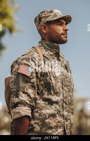 Patriotic young soldier standing at attention outside his home. Courageous American serviceman coming back home after serving his country in the milit Stock Photo