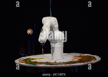 14 September 2022, Saxony-Anhalt, Magdeburg: The cleaning robot 'Putzini' (l) and the industrial robot 'Arka' (r) perform during a rehearsal for the drama 'Nessun Dorma'. The two robots have been part of the acting ensemble at Theater Magdeburg since this season. In the drama, the location of the action is reportedly an art gallery. The industrial robot Arka paints there to the sounds of well-known death arias. When the visitors have left the exhibition rooms in the evening, the robot Putzini, screwed together from everyday objects, moves around. The two meet and exchange ideas about art, love Stock Photo