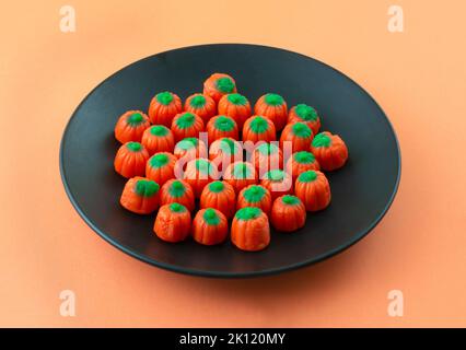 Halloween pumpkin candy snack on black plate on orange background Stock Photo