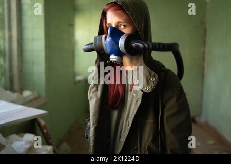 Post apocalypse concept. A woman in a gas mask walks in an abandoned building among the ruins. Chemical warfare, air pollution. Poor environmental con Stock Photo