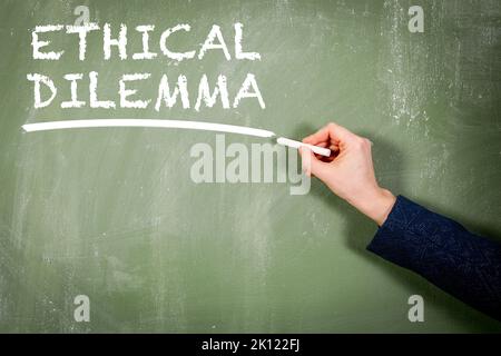 Ethical Dilemma. Woman's hand writing text on a chalkboard. Stock Photo