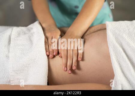 relaxing massage and body shaping massage, lymphatic drainage, manual and aesthetic procedures, hands massaging belly in the spa Stock Photo