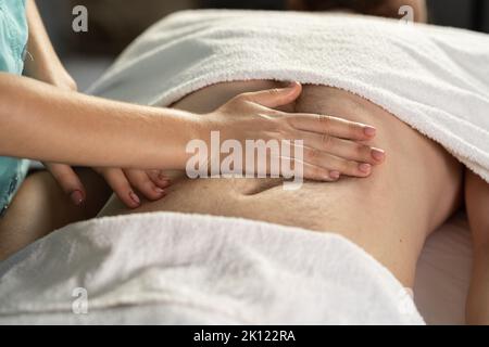 Professional relaxing massage and body shaping massage, lymphatic drainage, manual and aesthetic procedures, hands massaging belly in the spa Stock Photo