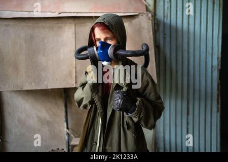 Post apocalypse female survivor in gas mask on wall background. Stock Photo