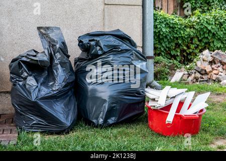 Black garbage bags on the wall of the building. Garbage collection. Stock Photo