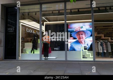 Marks and Spencer windows with colour picture of Her Majesty Queen Elizabeth II wearing a hat on display. Text 1926-2022. Manchester UK. Stock Photo