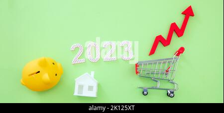 2023 year, Living cost, groceries and food price rising up, saving. Shopping cart piggy bank and red arrow up. Stock Photo