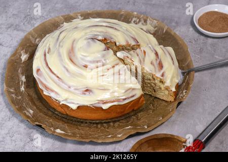 giant cinnamon roll with buttercream frosting,, grey marble table Stock Photo