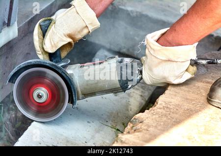 A worker with a circular saw cuts a concrete block in close-up. Stock Photo