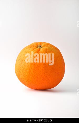 Ripe whole orange fruit detail isolated on white table. Vertical composition. Stock Photo