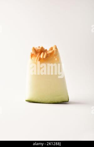 Ripe melon cut detail on white table with white isolated background. Front view. Vertical composition. Stock Photo