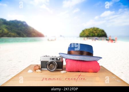 Idea concept. Red pink tower, blue hat, old vintage camera and shells over wooden floor on sunshine blue sky and ocean background. Stock Photo