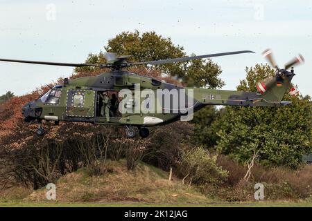 Crew chief hanging out of a German Army NH90 helicopter taking off from Deelen airbase during Falcon Autumn exercise. Deelen, The Netherlands - Octobe Stock Photo