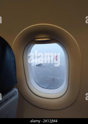 A view through a raindrop glass from a window seat in the airplane on the rainy day at the airport. Stock Photo