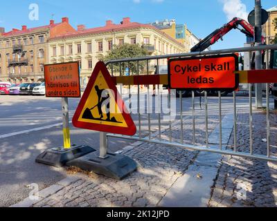 Halmstad, Sweden - August 20, 2022: Road works sign on city street and information board in Swedish language that directs cyclist to the other side of Stock Photo