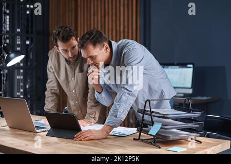 young colleagues working on their new project late at night. Stock Photo