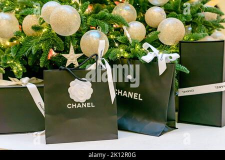 Moscow, Russia - December 15, 2021 - Chanel logo on black paper bags with presents under christmas tree. Luxuary brand of clothes, accessories and cos Stock Photo