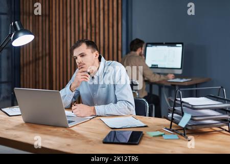 tired man working late at night on a new project. Stock Photo