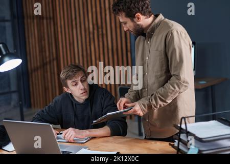 tired colleagues working in the office late at night . Stock Photo