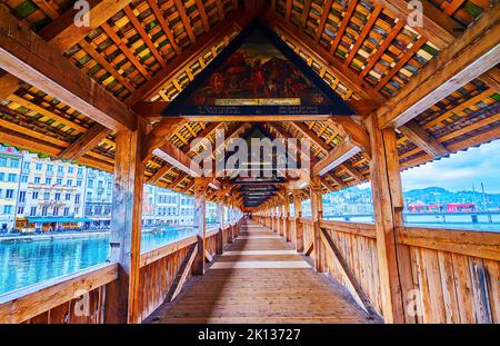 Medieval pictures under the roof of covered wooden Kapellbrucke bridge across Reuss river in Lucerne, Switzerland Stock Photo