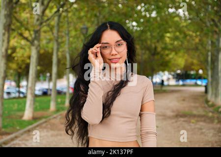 Young latin girl holding her glasses and smiling looking ar camera. Stock Photo