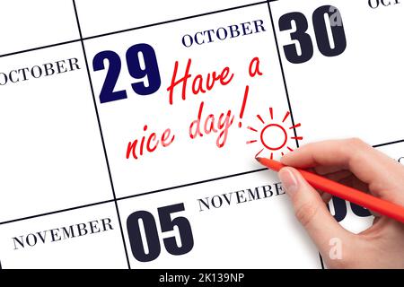 29th day of October. The hand writing the text Have a nice day and drawing the sun on the calendar date October 29. Save the date. Autumn month, day o Stock Photo