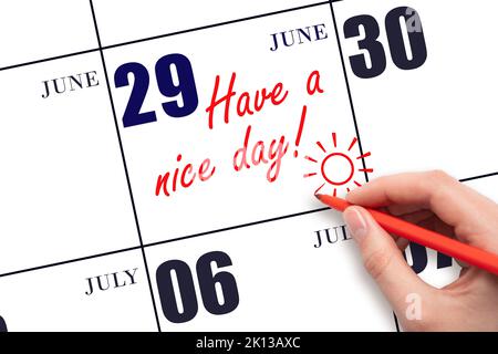 29th day of June. The hand writing the text Have a nice day and drawing the sun on the calendar date June 29. Save the date. Summer month, day of the Stock Photo