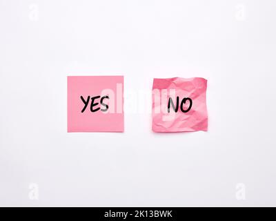 The words yes and no on pink sheets of note paper. Say or choose yes concept Stock Photo