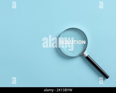 Magnifier focuses on the word solution. Searching for a business solution concept. Stock Photo