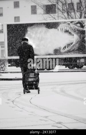 A vertical grayscale shot of an old man with baggage during snow Stock Photo