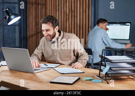 smiling business man working on a laptop in a night office. Stock Photo