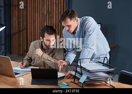 young businessmen working in the office together at night . Stock Photo