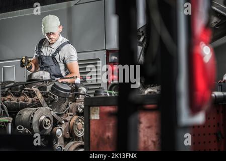 Caucasian Middle Aged Mechanic with a Screwdriver in His Hand Checking and Repairing Large Coach Engine in His Car Repair Shop. Vehicle Maintenance Th Stock Photo