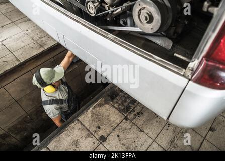 Caucasian Mechanic Standing in the Inspection Pit at Vehicle Control Station Performing Regular Technical Check of the Long Distance Motor Coach. Engi Stock Photo