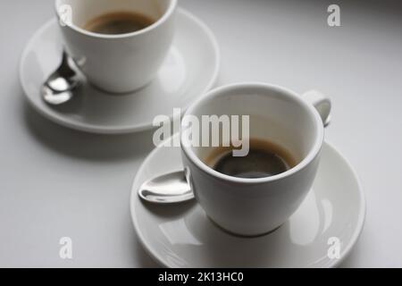 Two Cups of Hot Fresh Espresso Shots on White Table Background. Brewing, Drinking Coffee. Stock Photo