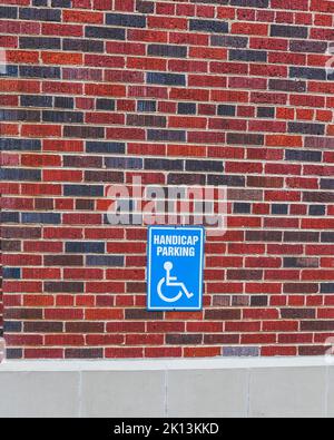 A handicap parking sing on a red and black brick wall Stock Photo