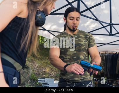 Shooting instructor teaching a women how to properly handle a weapon at ...