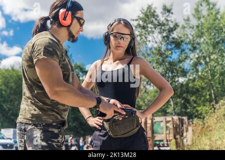 young woman and man practicing target shooting at the shooting range, medium shot. High quality photo Stock Photo