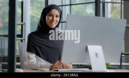 Confident successful elegant arab businesswoman typing on computer attractive muslim female in hijab professional worker experienced manager Stock Photo